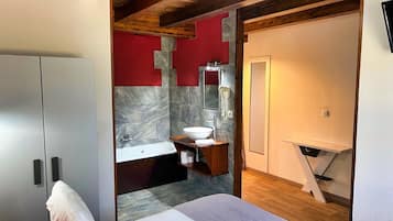 Ein modernes Badezimmer mit Marmorwand, Waschtisch aus Holz, weißem Waschbecken und großem Spiegel.