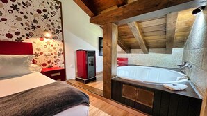 A bedroom with a bed, a red cabinet, a red heater, and a large bathtub. - Apartamentos Spa Casco Histórico de Isla (Isla)