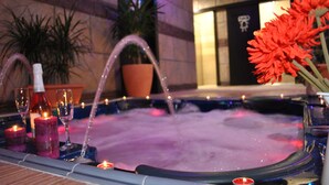 A hot tub with candles and flowers, surrounded by potted plants and a tiled wall. - Apartamentos Spa Casco Histórico de Isla (Isla)