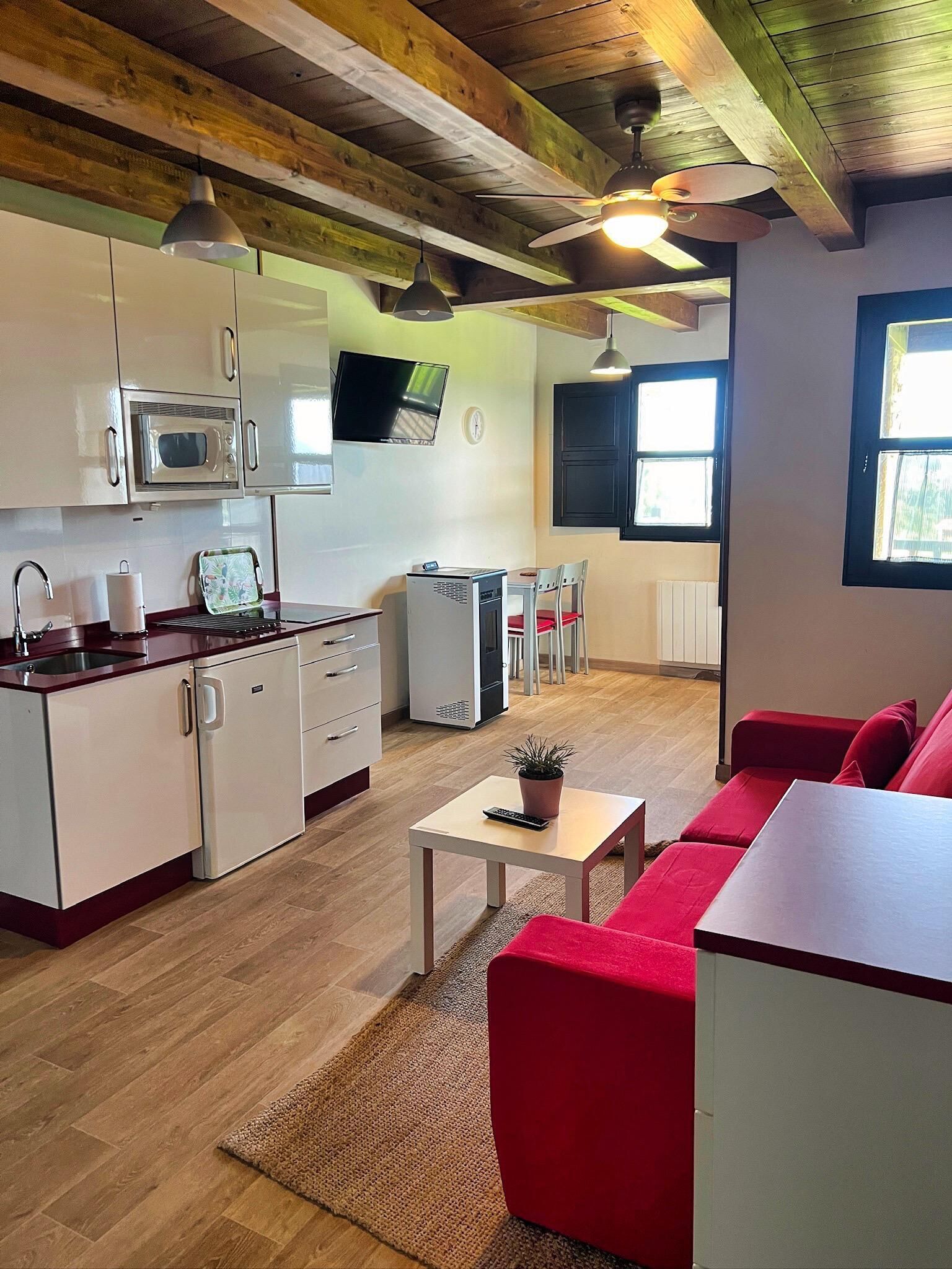 Espai habitable compacte amb bugateria, zona de dinar i zona d'estar amb un sofà vermell.