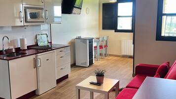 Espai habitable compacte amb bugateria, zona de dinar i zona d'estar amb un sofà vermell.