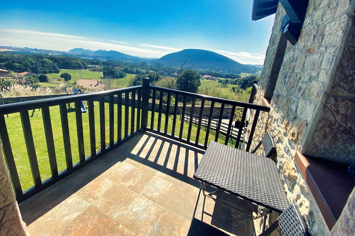 Un balcón con vistas a un paisaje verde y montañas distantes.