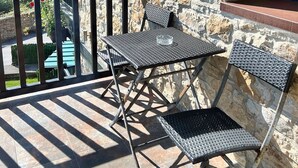 A stone building with a balcony featuring two metal chairs and a table. - Apartamentos Spa Casco Histórico de Isla (Isla)