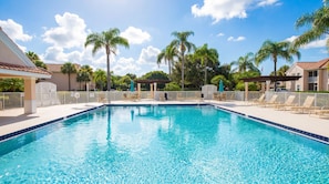 A swimming pool with lounge chairs and palm trees.