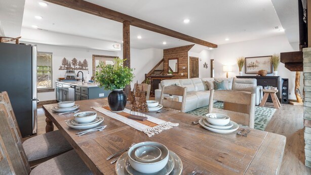 A spacious living area with a wooden dining table set for four, a sofa, and a fireplace. - Cozy Cabin with Private Hot Tub, Fireplace & Community Amenities Near Thunder Ridge & Table Rock (Hollister)