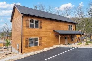 Ein zweistöckiges Holzhaus mit überdachter Veranda und Parkplatz.