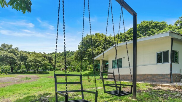 A building with a porch and two swings in a grassy area. - Finca Brisas de la Montaña (Coco)