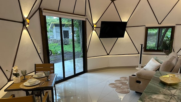 Un salon moderne comprenant un coin repas, un canapé et un téléviseur fixé au mur.