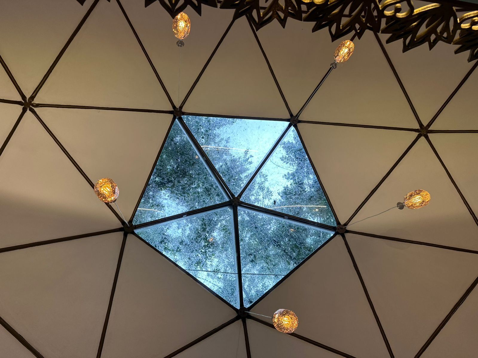 A geometric ceiling design with a central skylight revealing a snowy landscape.