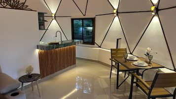 Una cocina moderna con una isla central, un comedor con mesa y sillas, y una zona de estar con sofá y una mesita auxiliar.
