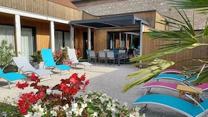 Un patio con sillones, una mesa y un espacio de estar cubierto.