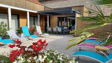 Un patio con sillones, una mesa y un espacio de estar cubierto.