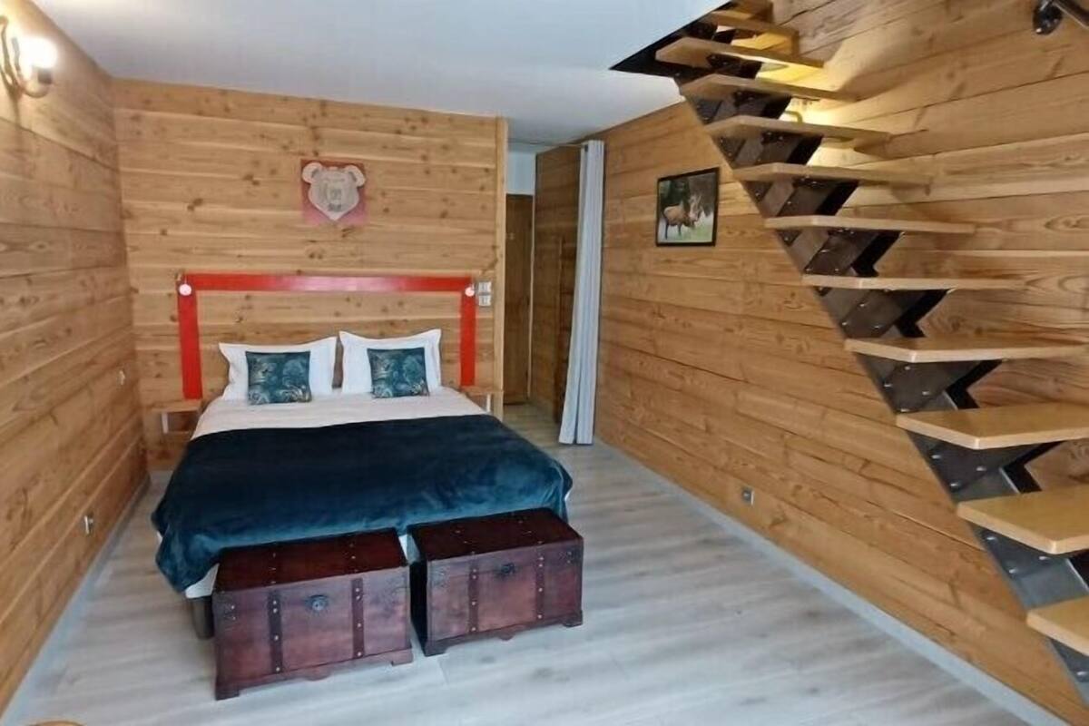 Un dormitorio con paneles de madera, una cama, un cabecero y una escalera.