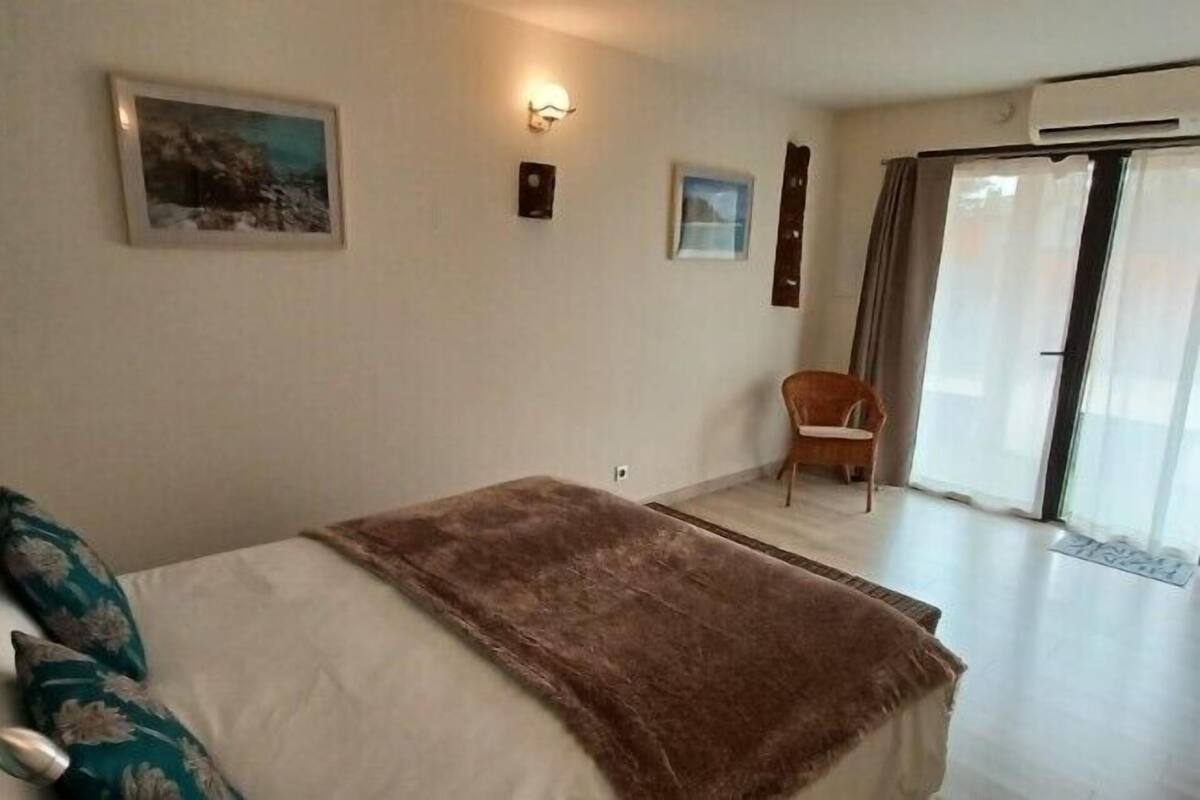 Un dormitorio con cama, una silla, una ventana y una puerta.