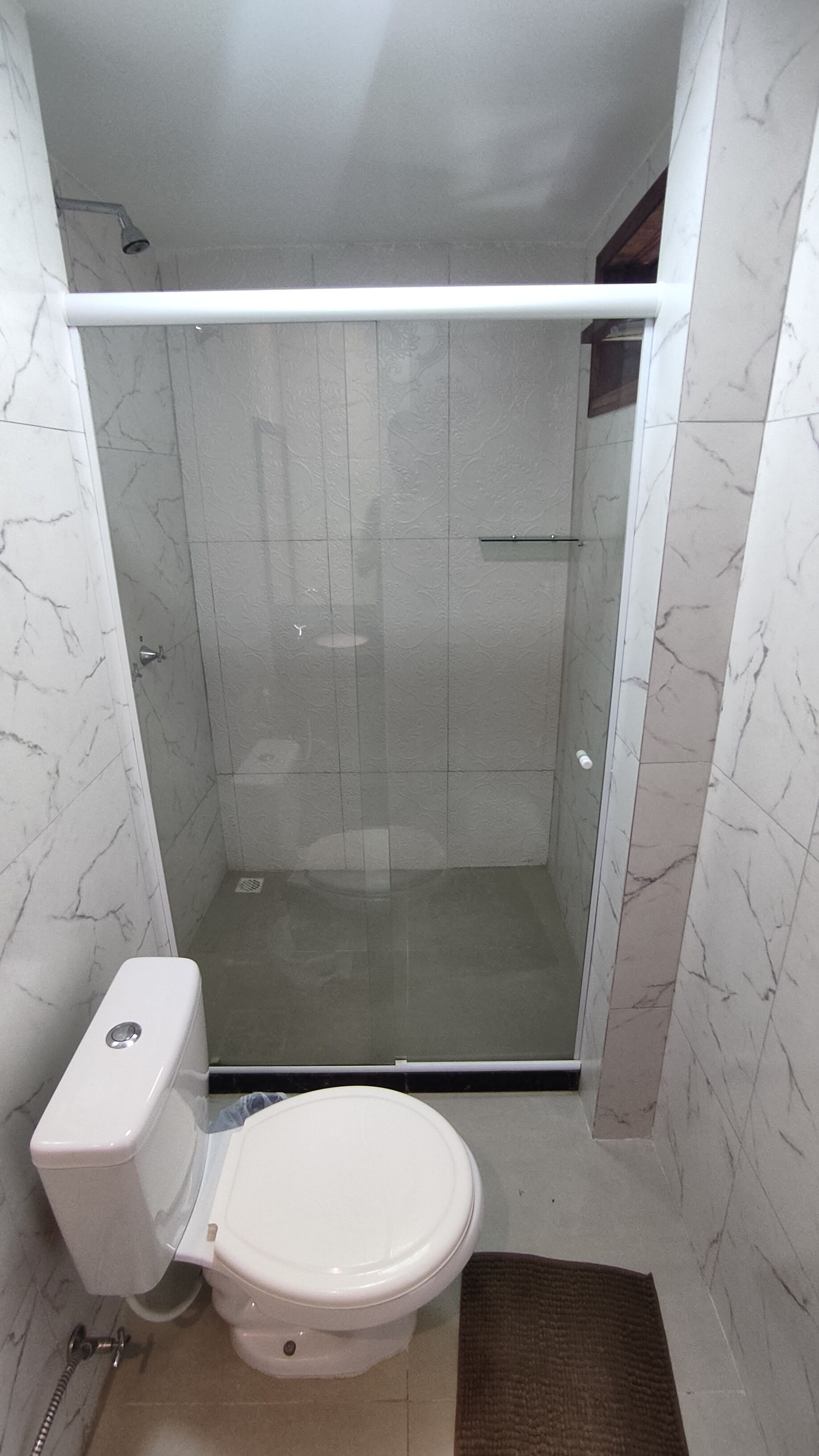 A bathroom with a toilet, shower, and marble walls.