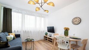 Un salon moderne avec un canapé, un téléviseur, une table à manger et des chaises.