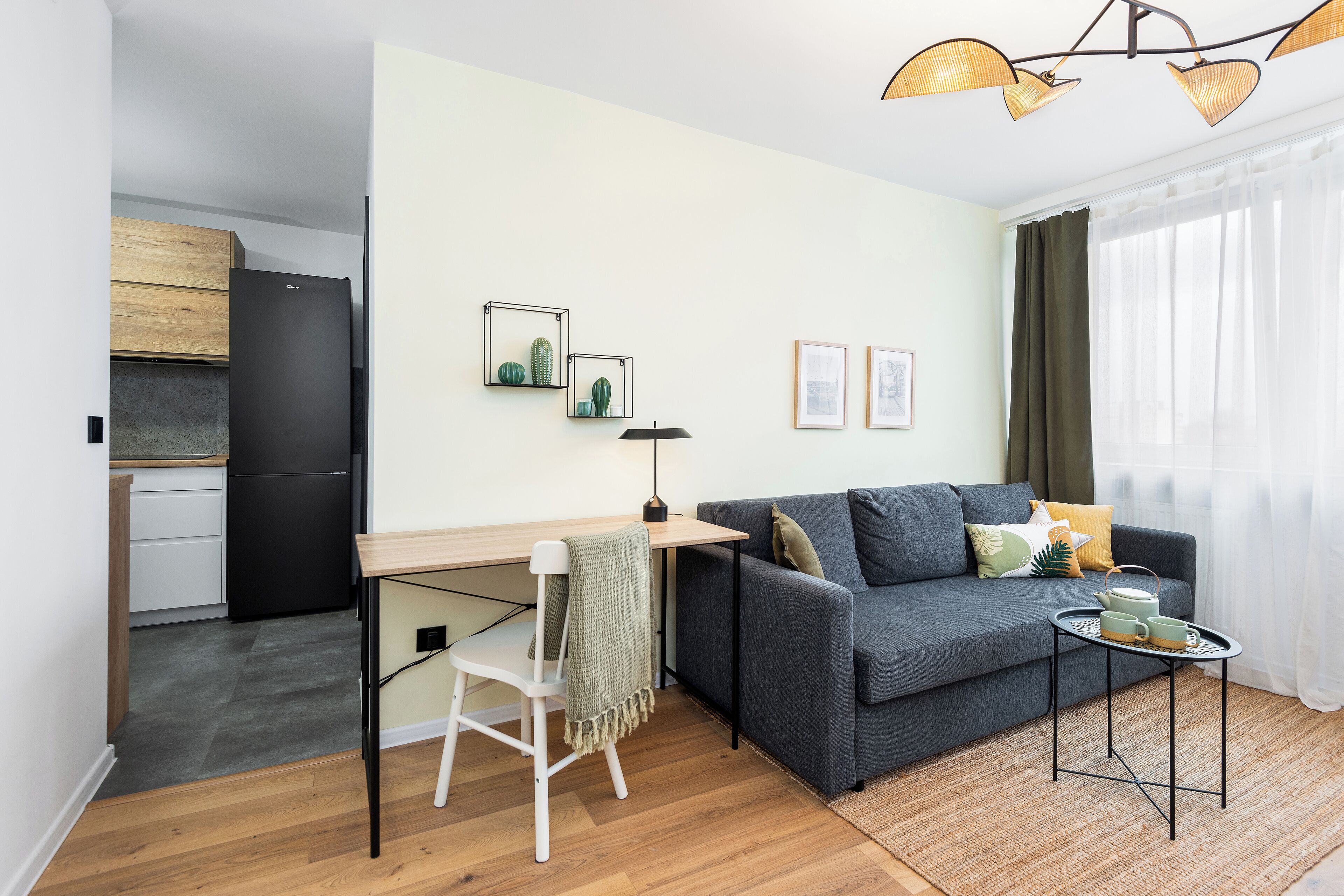 A compact living space with a kitchenette, a sofa, a small table, and a chair.