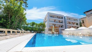 A modern hotel with a swimming pool, sun loungers, and a clear blue sky. - Hotel Besani (Durrës)