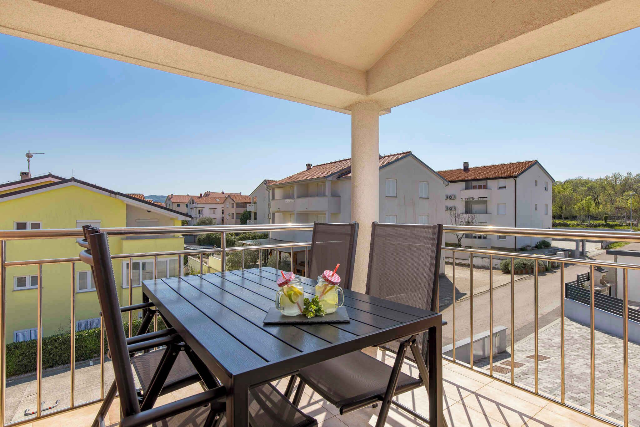 A balcony with a table and chairs, two drinks on the table, and a view of neighboring buildings.