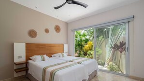A bedroom with a large bed, a ceiling fan, and a sliding glass door leading to a garden. - Private condo ideal for group/family, 12 people (Tulum)