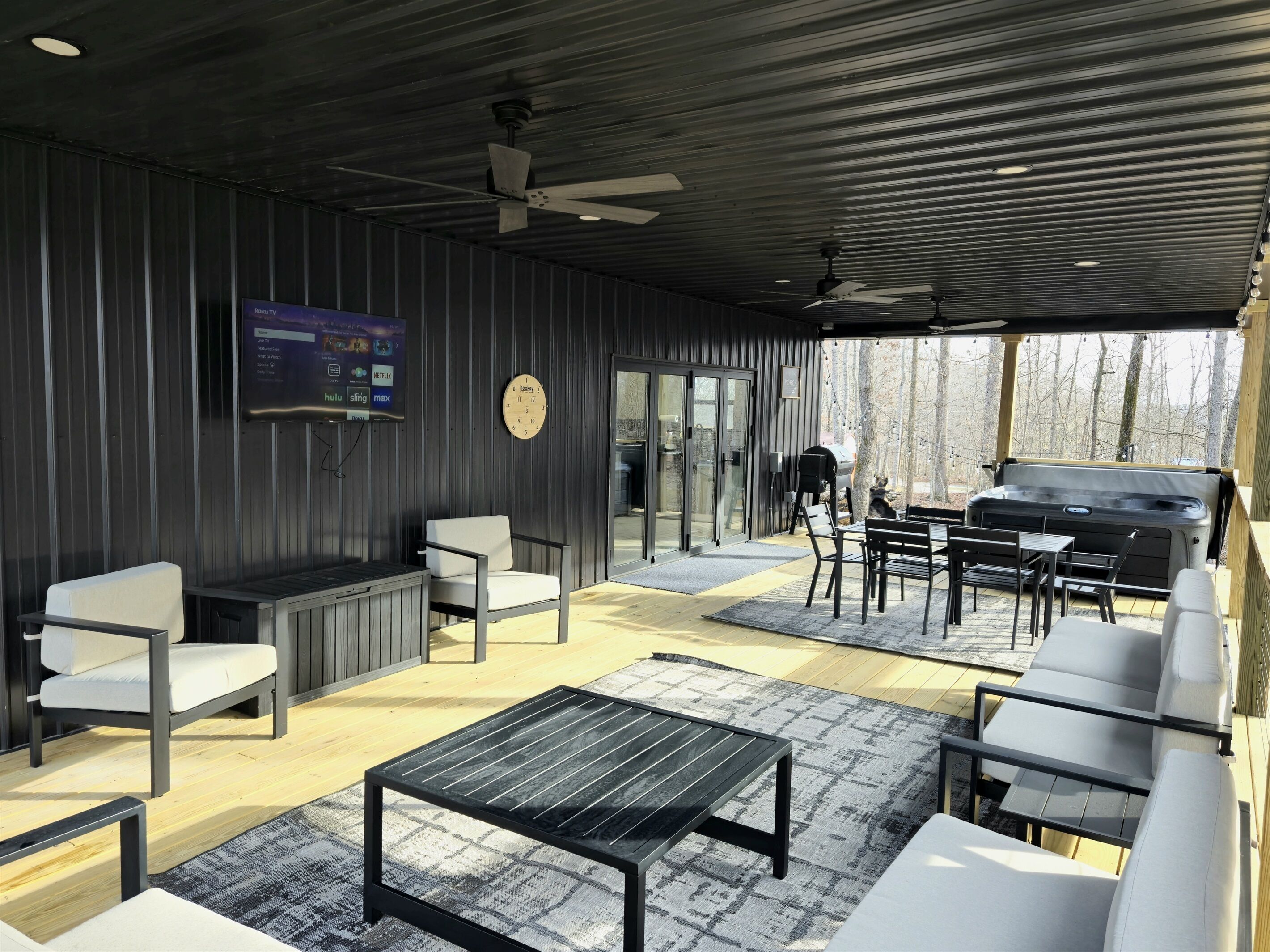 A covered outdoor area with seating, a grill, and a TV screen displaying streaming services.