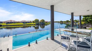 A modern outdoor pool area with clear views of a lake and surrounding greenery. - 4 bedroom 3 bathroom house on canal, sleeps 12, pool (Wurtulla)