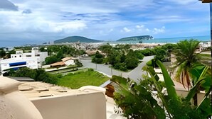 A balcony with a view of a coastal cityscape, including buildings, greenery, and a beach. - Cobertura Triplex no Guarujá SP 1 (Guaruja)
