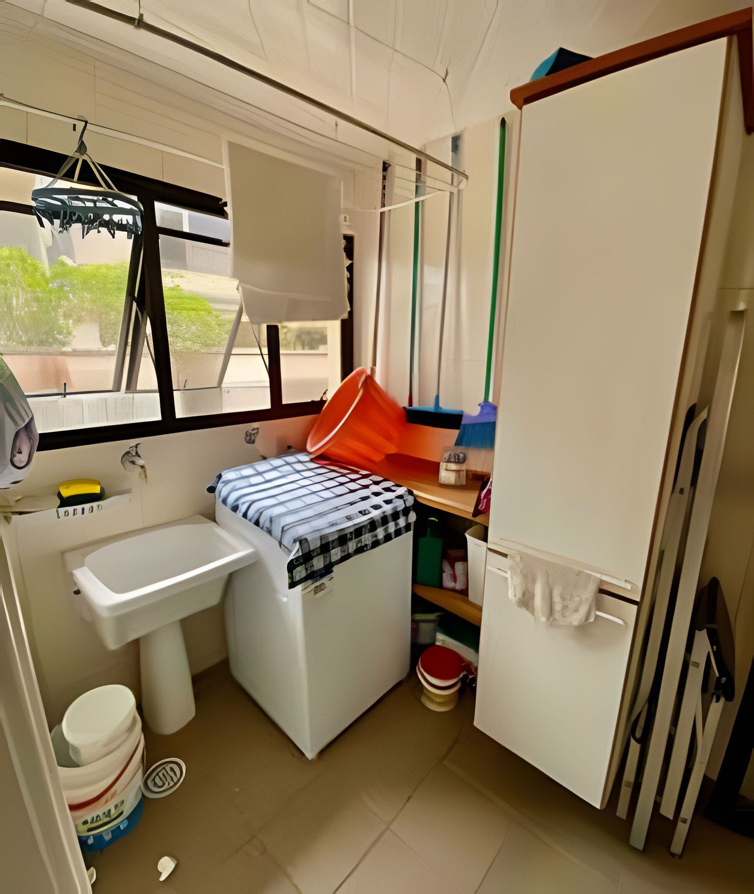 A compact kitchen with a sink, a small countertop, a window with a view, and a refrigerator.