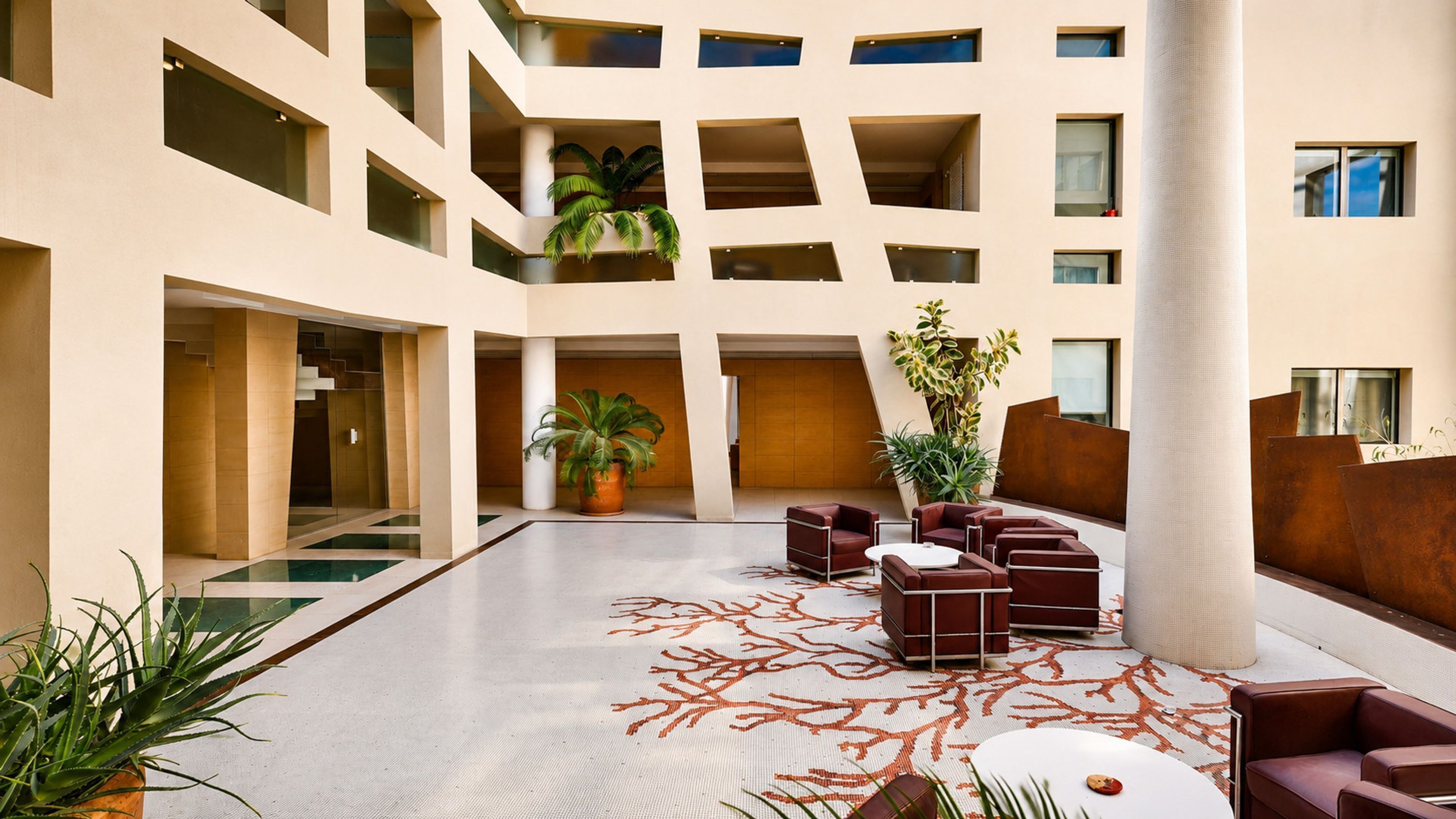A spacious atrium with a central seating area, multiple balconies, and potted plants.