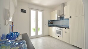 Una cocina moderna con armarios blancos, salpicadero de azulejos azules y un ventanal grande.