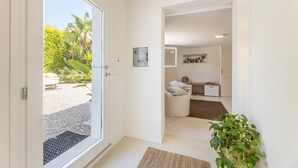 Ein modernes Interieur mit einer Tür, die auf einen Balkon führt, einer kleinen Sitzecke und einer Küchenzeile.