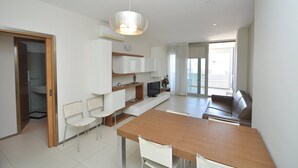 Uma cozinha moderna com armários brancos, uma mesa de jantar de madeira e uma televisão integrada.