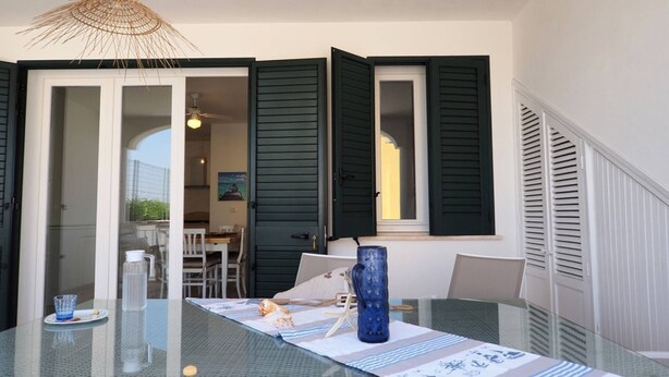 A glass table with a blue water bottle, a white vase, and a starfish decoration. - Villa DEL Mare 2 in Torre San Giovanni (Ugento)