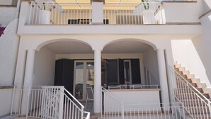 A two-story building with a balcony, white railings, and a staircase. - Villa DEL Mare 2 in Torre San Giovanni (Ugento)