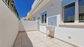 A narrow outdoor corridor with tiled flooring, a white wall, a blue window, and a white sink. - Corte 1 in Residence With 4 Beds - 2 Bedrooms (Taviano)