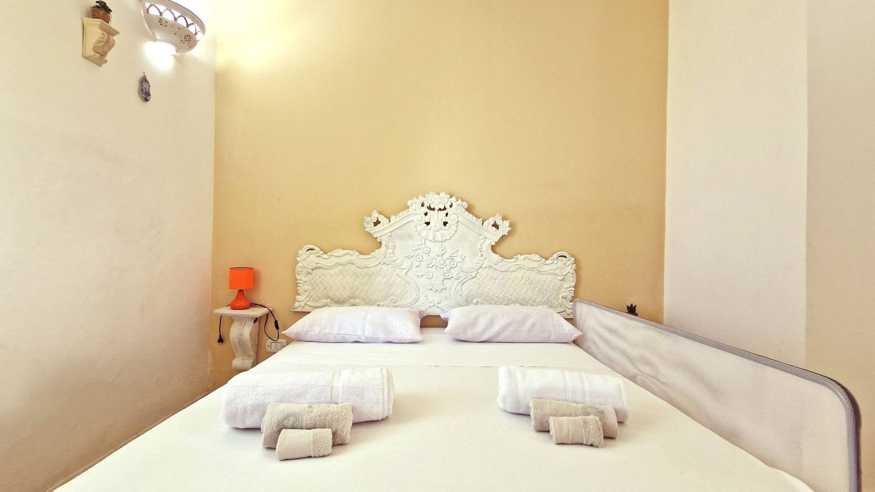 A bed with a white headboard, two white pillows, and several folded towels.