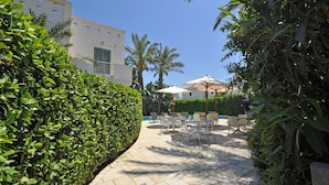 A courtyard with a tiled floor, outdoor seating, and palm trees. - Residence Arainn Kalepolis - Pool Sleeps 5 Wifi (Ugento)