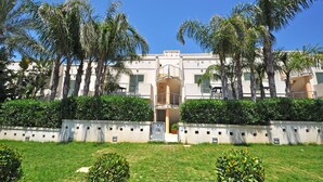 A building with a central courtyard, surrounded by palm trees and greenery. - Residence Arainn Kalepolis - Pool Sleeps 5 Wifi (Ugento)