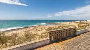 Une vue sur la côte, avec une plage de sable, un ciel dégagé et une balustrade en pierre.