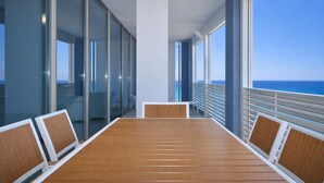 A cruise ship interior with a wooden table, white cushioned chairs, large windows, and a view of the ocean. - Appartamento LE 5 Vele (Gallipoli)
