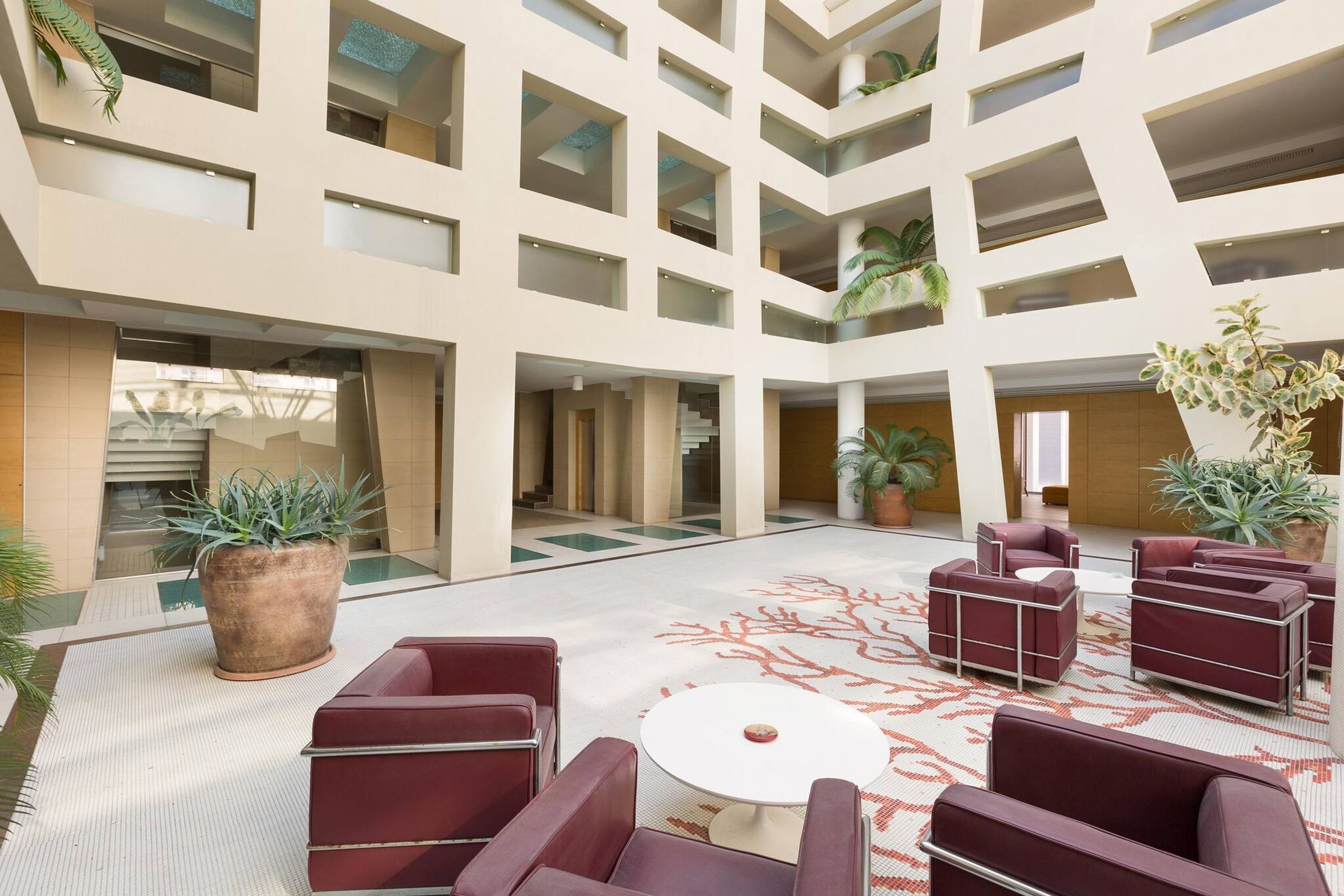 A spacious atrium with a central seating area, multiple levels, and potted plants.