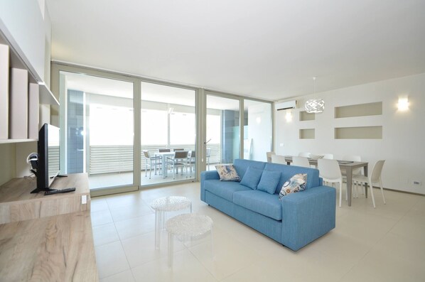 A modern living room with a blue sofa, a coffee table, and a TV on a wooden stand.