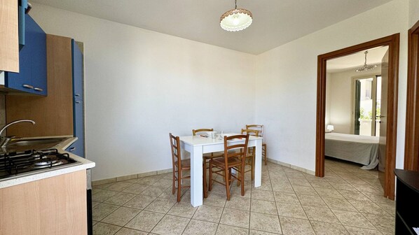 Una cocina compacta con una mesa y sillas, estufa y una lámpara colgante.
