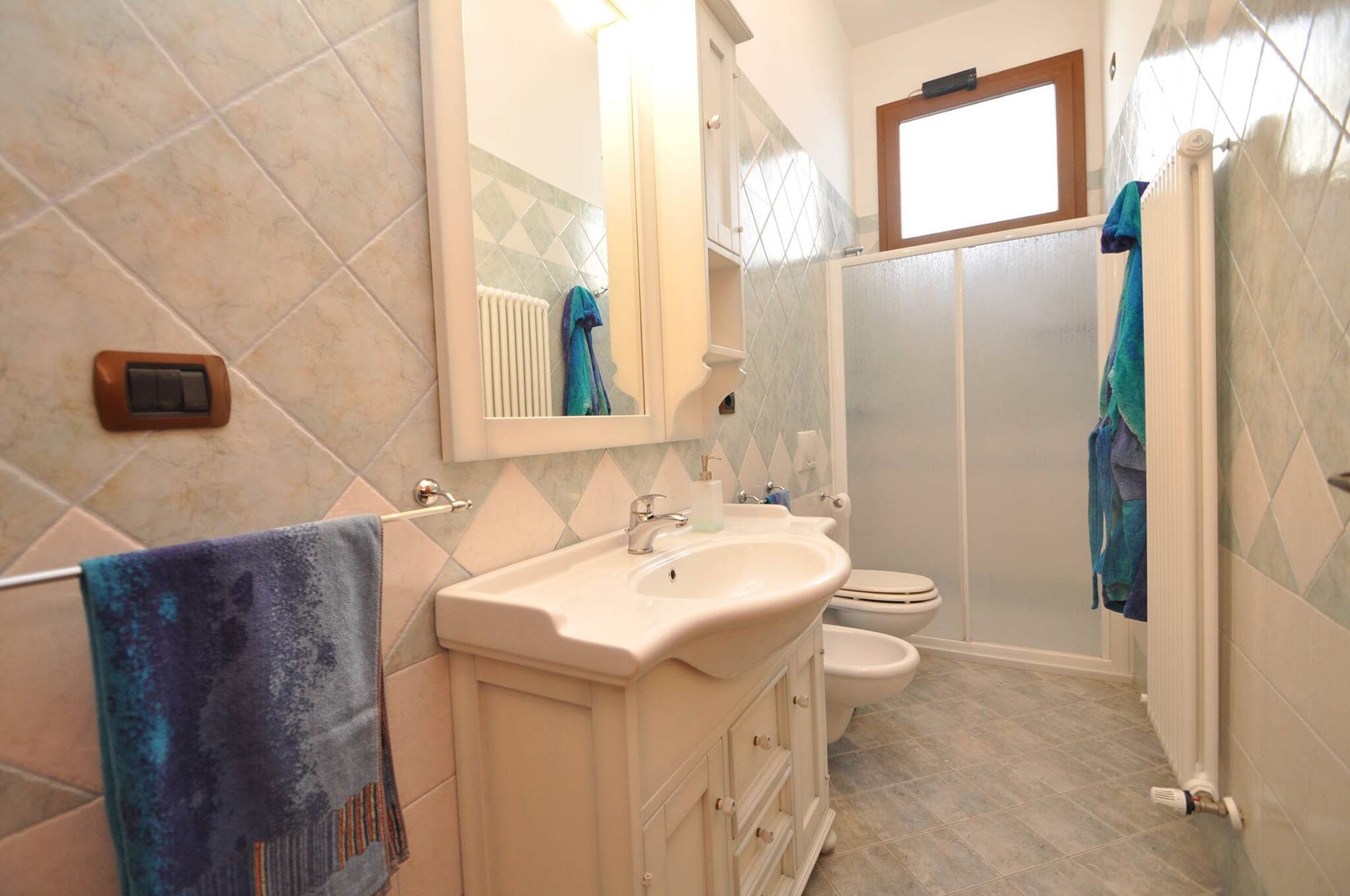 Ein Badezimmer mit Waschbecken, Spiegel, zwei Toiletten und einer Dusche.