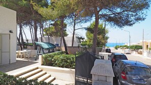 A coastal residential area with a paved walkway, outdoor seating, and parked cars. - Villa Marechiaro 50 m From the sea 3 Bedrooms 2 Bathrooms (Racale)