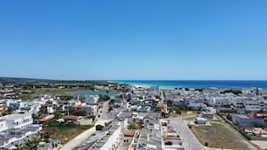 Eine Küstenstadt mit weißen Gebäuden, einer Straße und einem Strand im Hintergrund.