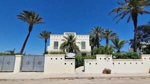 A modern two-story building with a flat roof, surrounded by palm trees and a gated entrance. - Bilocale Arainn 2 - Japigia (Ugento)