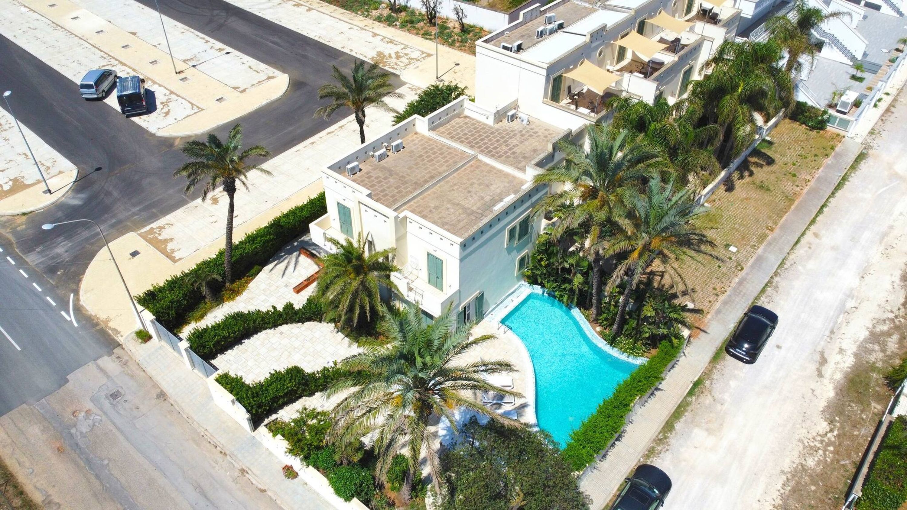 Un bâtiment moderne doté d’une piscine entourée de palmiers.