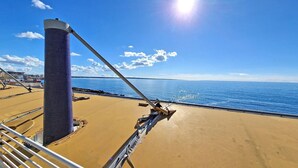 Das Deck eines Schiffes mit einer großen zylindrischen Struktur, einem Metallgeländer und Blick auf den Ozean.