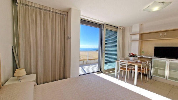 Ein modernes Hotelzimmer mit Balkon, Essbereich und Fernseher.